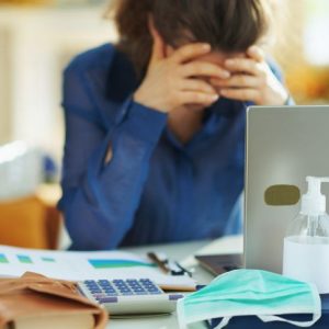 One Debt | Take The First Step | woman-at-desk-thumbs-to-temples